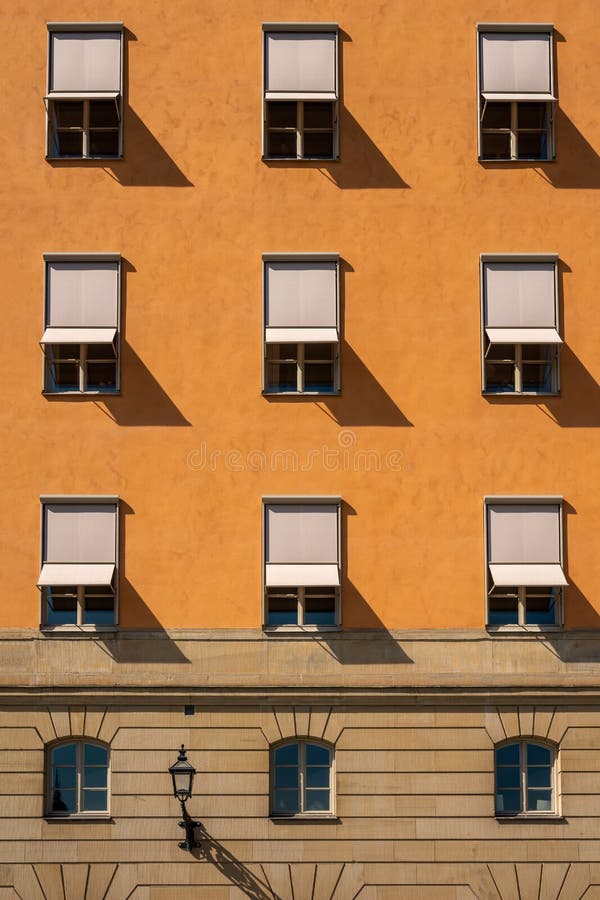 Front view of many symmetrical windows with sun blinds on a stone city building. royalty free stock image