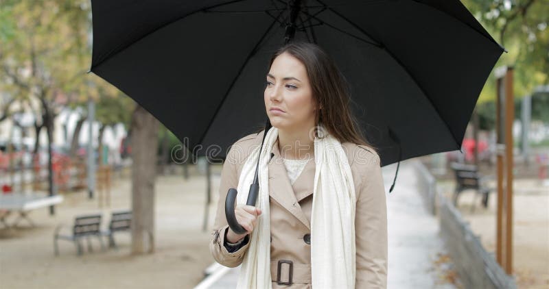 Frustrated woman walking complaining under the rain