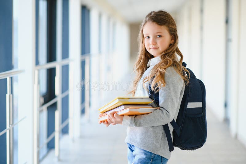 Front view of pretty blonde school girl holding many colorful notes and books. Clever teen girl smiling at camera