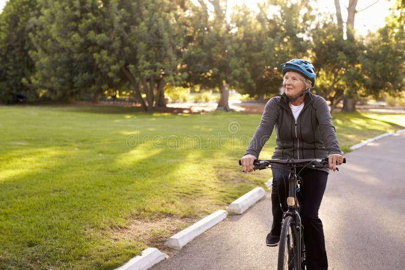 Front View Of Senior Woman som cyklar parkerar igenom royaltyfria bilder Front View Of Senior Woman som cyklar parkerar igenom royaltyfria bilder