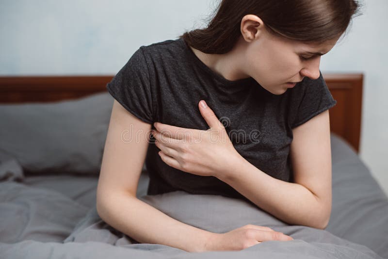 Front view of upset tired young woman feeling pain ache touching chest having heart attack