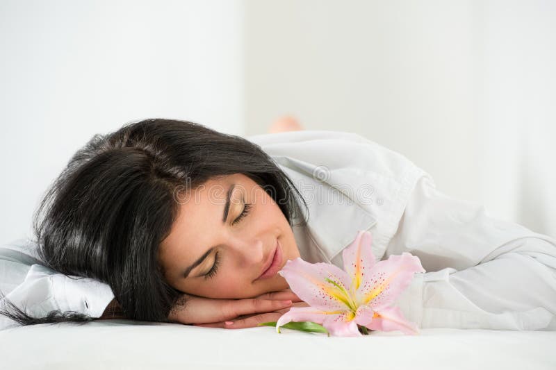 Front View of Young Woman Sleeping on Massage Table in Spa Stock Photo