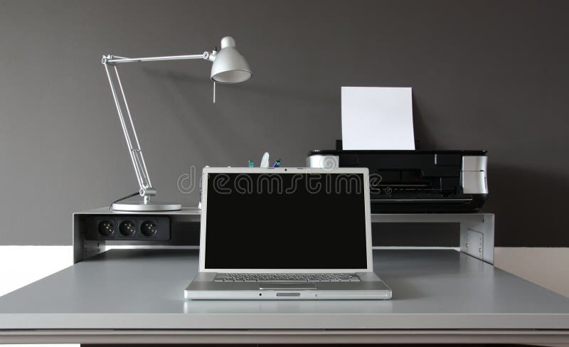Čelní Domů kancelářský stůl s notebookem a tiskárnou.