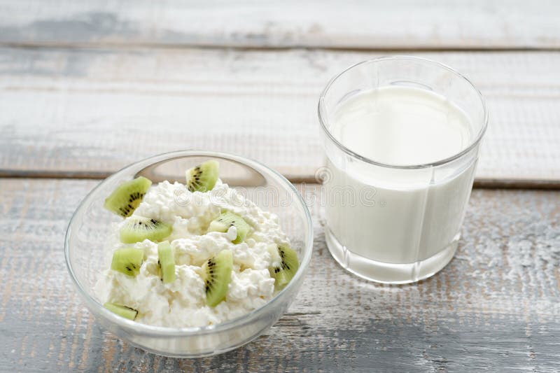 Frontal no requeijão de madeira cinzento do fundo na bacia com fruto de quivi, luz suave, conceito saudável do alimento imagens de stock Frontal no requeijão de madeira cinzento do fundo na bacia com fruto de quivi, luz suave, conceito saudável do alimento imagens de stock