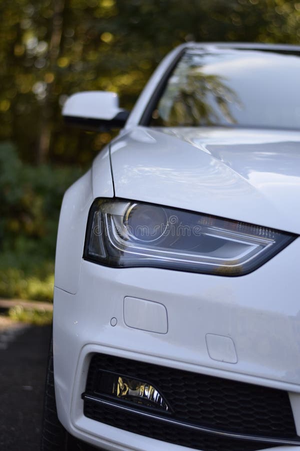 Frontal View of a Headlight of a Parked White Car Editorial Stock Image