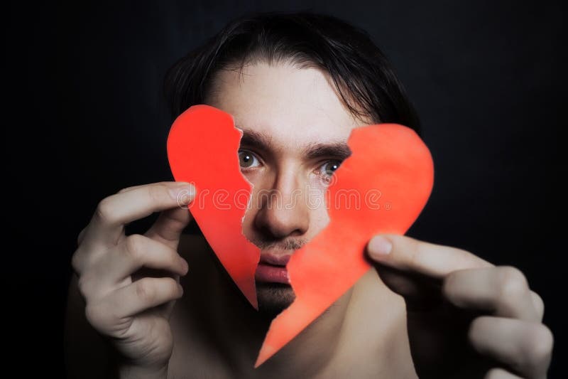 Fronte di giovane uomo bello con cuore di carta rotto fotografia stock