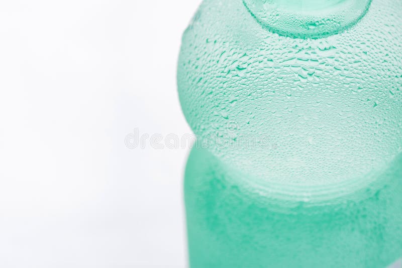 Frosty Bottle sudado verde claro con agua fresca pura clara en el fondo blanco Refresco del verano de la hidración