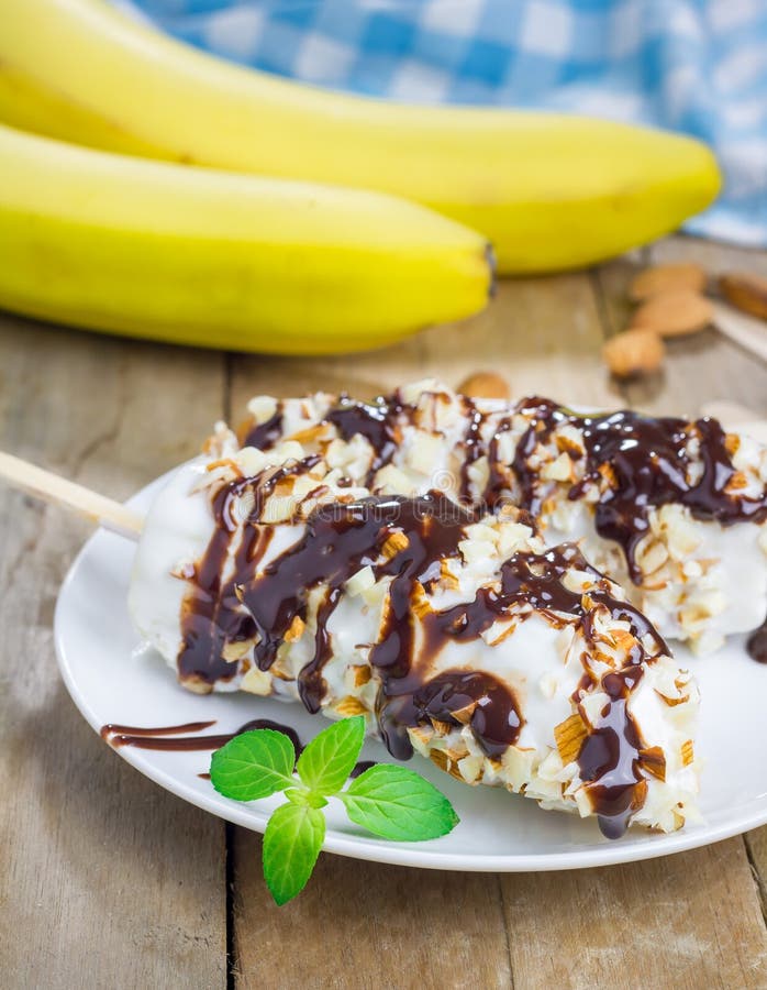 Frozen Banana Covered with Yogurt, Almonds and Chocolate Syrup Stock