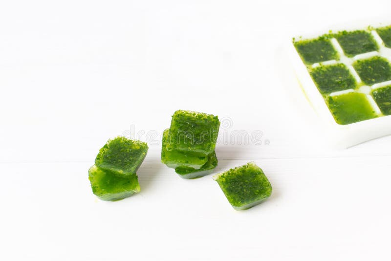 Frozen Basil Leaves in Ice Cubes with Fresh Basil on a Table. Frozen