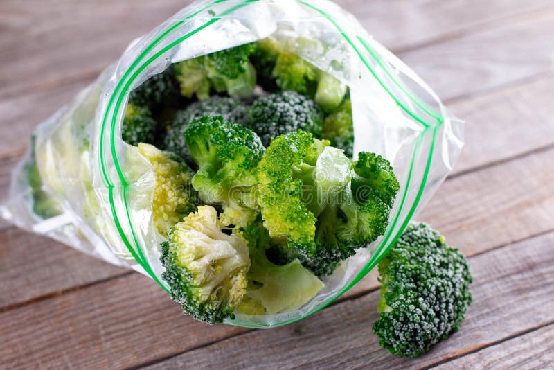 Frozen Broccoli Spilled Out of a Plastic Bag on Wooden Table Stock