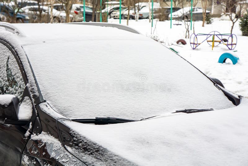 A Frozen Car Windshield is Covered in Ice and Snow on a Winter Day
