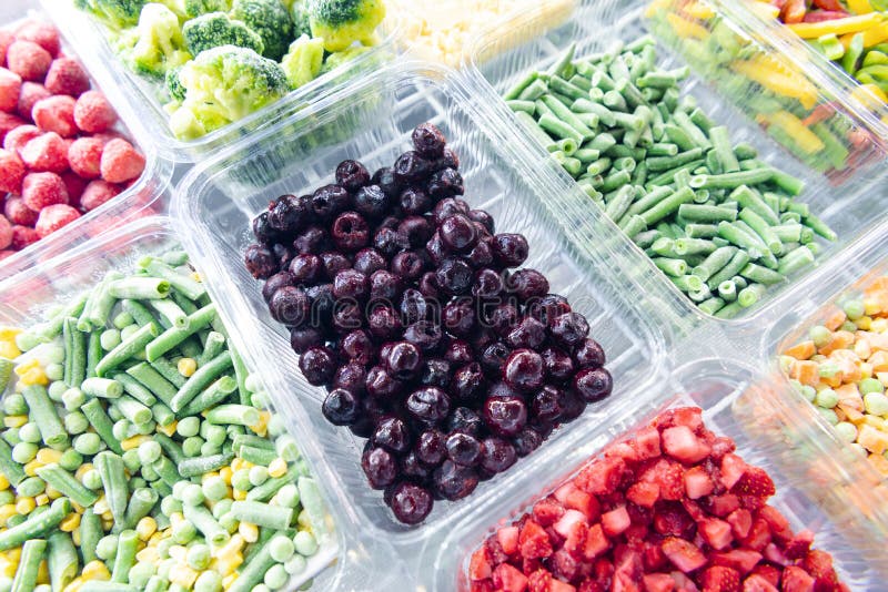 Frozen Cherry Berries. Freezing vegetables and fruits. Food products are poured into rectangular plastic trays.