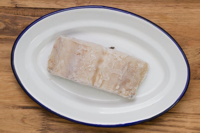 Frozen Cod Fish on White Dish on Brown Background Stock Photo Image