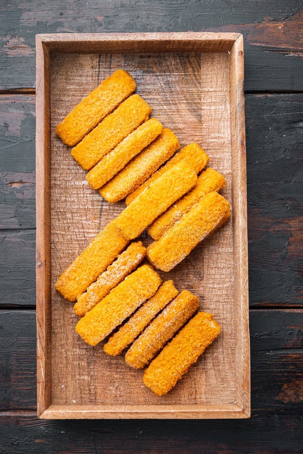 Frozen fish Sticks , in wooden box, on old dark wooden table background, top view flat lay stock photo