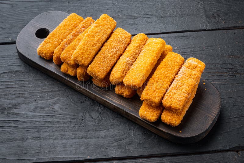 Frozen fish Sticks , on wooden cutting board, on black wooden table background royalty free stock photography
