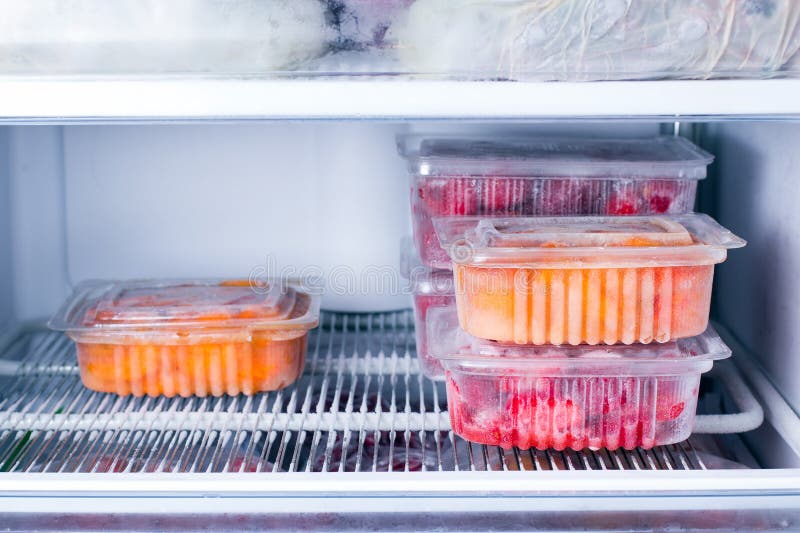 Frozen fruits and berries in a container in the freezer