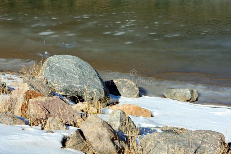 Frozen green river and rocks