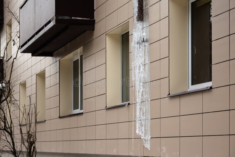 Frozen Rain Pipe on an Apartment Building. Ice on the Building Wall