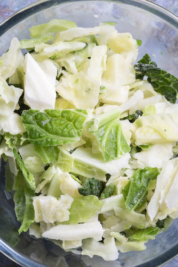 Frozen sliced cabbage defrosting in a glass bowl background. On a green marble background stock image