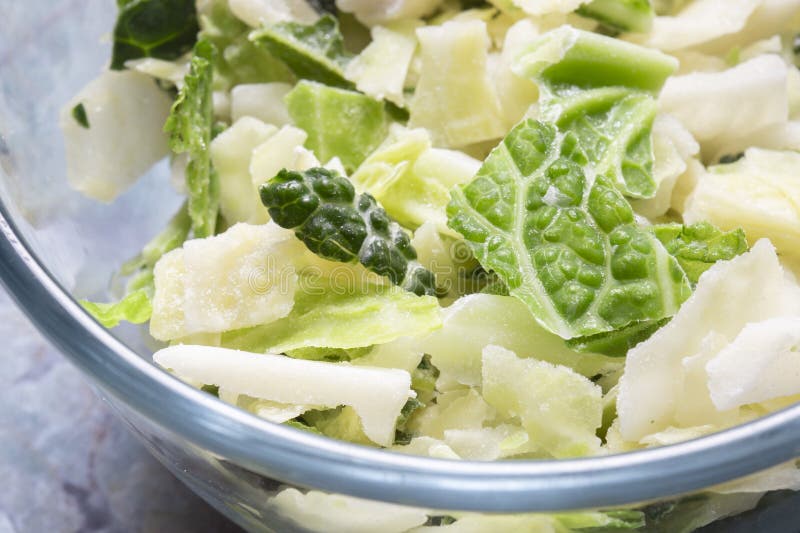 Frozen sliced cabbage defrosting in a glass bowl background. On a green marble background royalty free stock photography