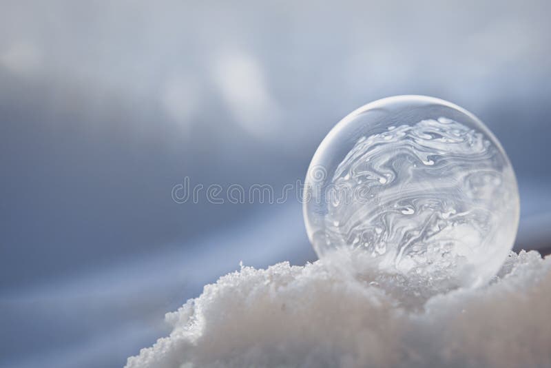 Frozen soap bubble with a beautiful pattern on the snow close-up on a blurry background. Soap snowflake stock images, royalty-free photos and pictures