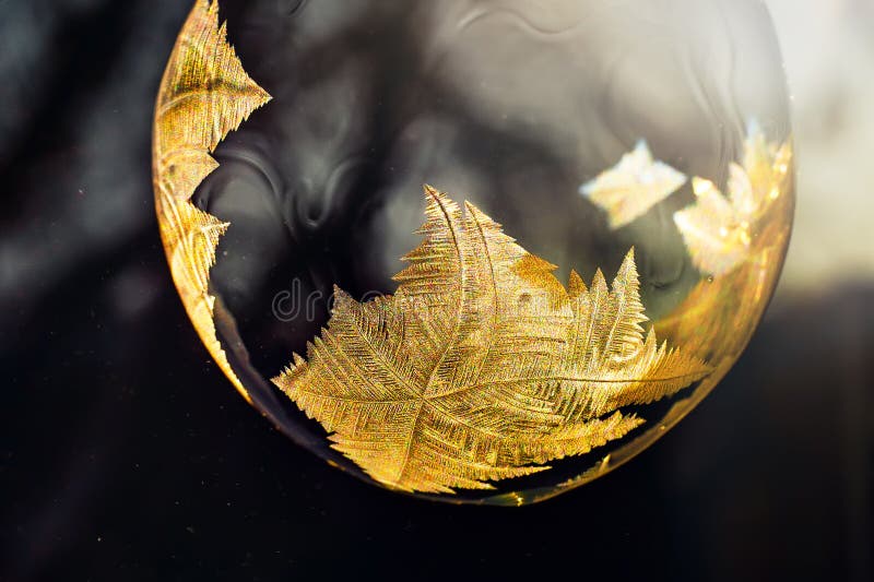 Frozen soap bubble with a beautiful pattern on the snow close-up on a blurry background. Frozen soap bubble with ice crystals at sunlight. Soap snowflake stock images, royalty-free photos and pictures
