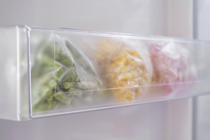 Frozen Vegetables in Plastic Bags in Freezer Closeup, Side View. Stock