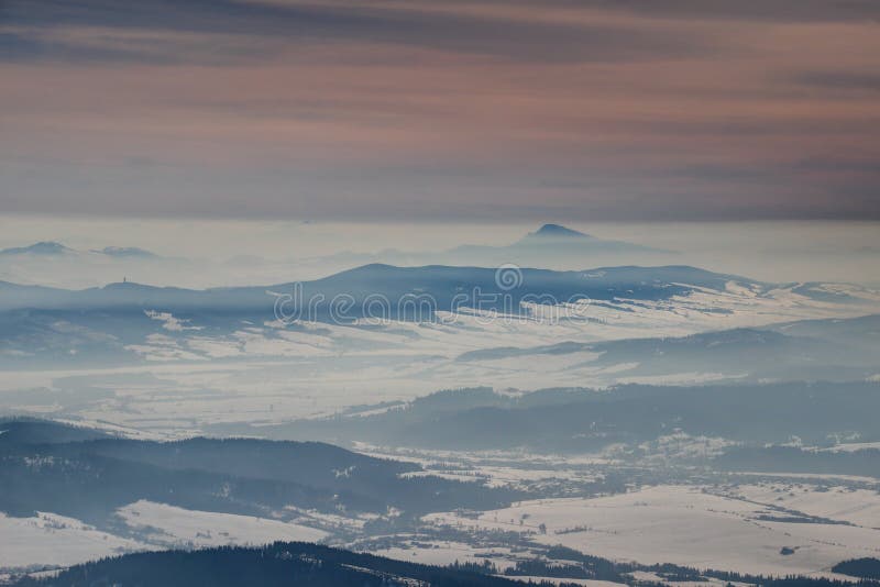 Frozen winter landscape with mountain ridges under orange sky