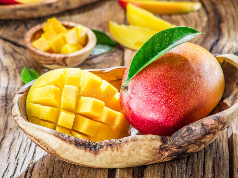 Mango fruit and mango cubes on the wooden table. Mango fruit and mango cubes on the wooden table.