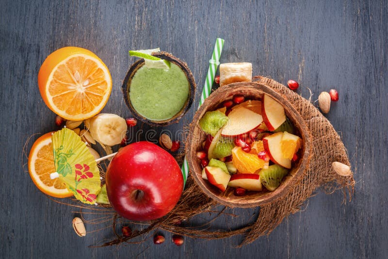 Fruit salad of apples, bananas, orange and pomegranate in half a coconut and fresh green smoothies from vegetables stock photo Fruit salad of apples, bananas, orange and pomegranate in half a coconut and fresh green smoothies from vegetables stock photo