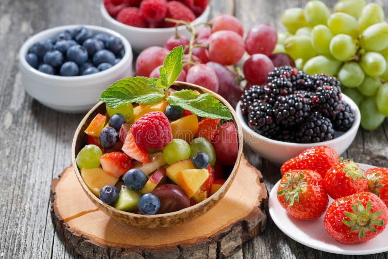 Fruit salad in a bamboo bowl and fresh berries