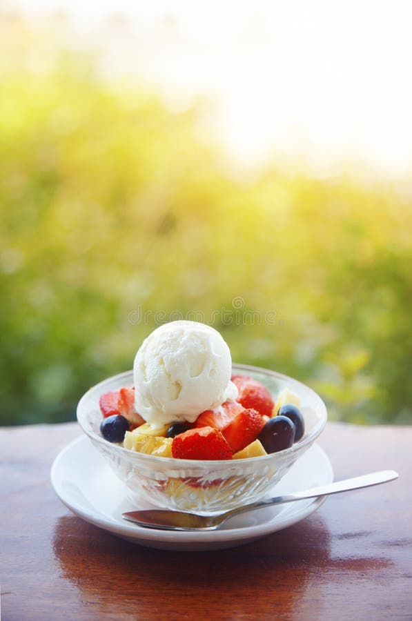 Fruit salad with ice cream on the table outdoors. Vertical photo with shallow depth of field for natural view. Vibrant colors