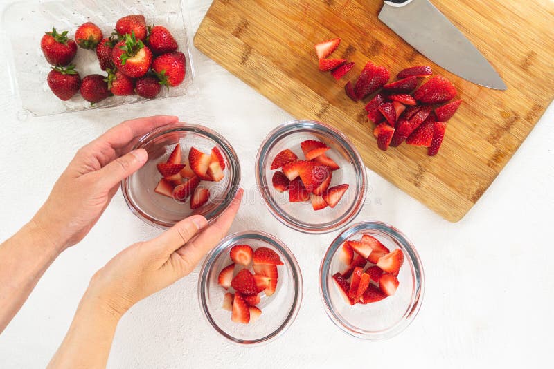 Sliced Strawberries in Clear Glass Bowls, Sliced Strawberries on a Chopping Board, Top View, Woman Hands, Fruit Salad, Dessert stock photos Sliced Strawberries in Clear Glass Bowls, Sliced Strawberries on a Chopping Board, Top View, Woman Hands, Fruit Salad, Dessert stock photos