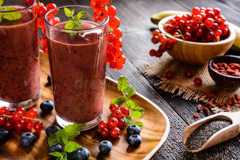 Fruit smoothies met rode aalbessen, bosbes, banaan, gojibessen en chiazaden stock fotografie Fruit smoothies met rode aalbessen, bosbes, banaan, gojibessen en chiazaden stock fotografie