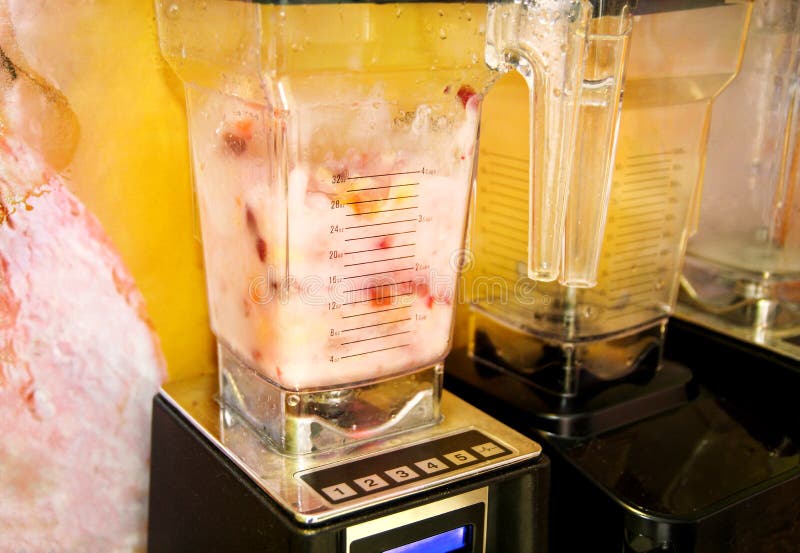 Fruit and vegetables smoothie in professional modern electric bl. Ender, closeup. Using blender for making a healthy smoothie. Worker is switching on high speed stock images
