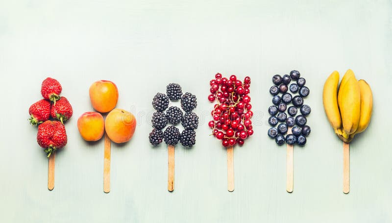 Fruits and berries assorted popsicles on light turquoise background, top view.Healthy food