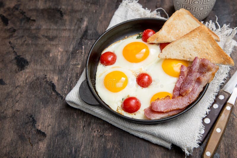 Frukostera med ägg, körsbärsröda tomater, bacon och nytt som rostas till arkivfoton Frukostera med ägg, körsbärsröda tomater, bacon och nytt som rostas till arkivfoton