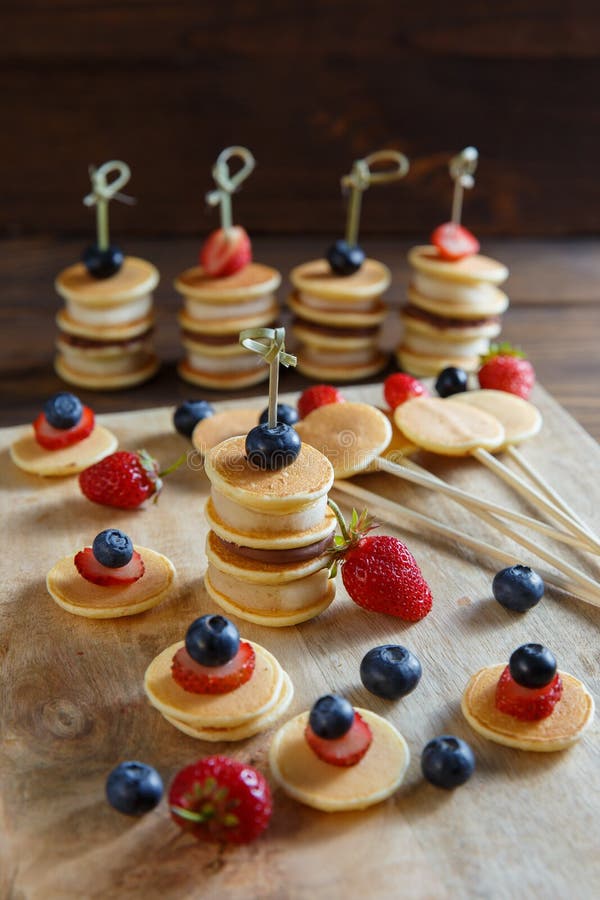 Frukt-, b?r- och pannkakacanapes p? den vita tr?tabellen arkivbilder Frukt-, b?r- och pannkakacanapes p? den vita tr?tabellen arkivbilder
