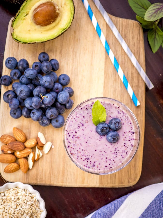 Frullato di mirtillo fresco con mandorle di avocado e fiocchi di avena in una tazza di vetro fotografia stock libera da diritti