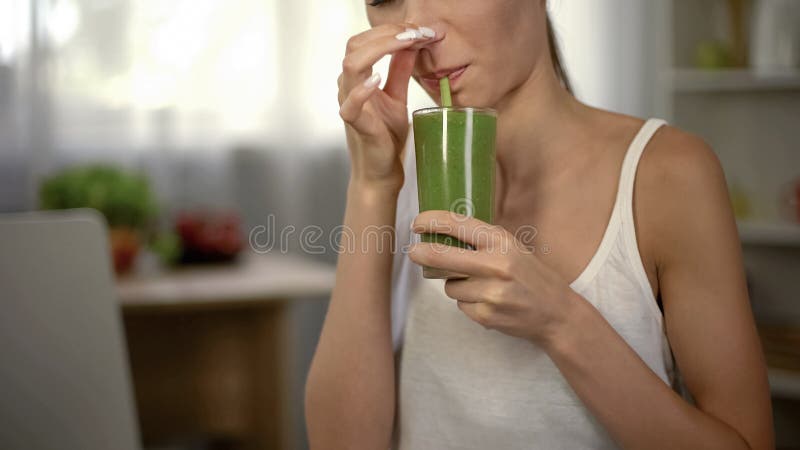 Frullato verde disgustoso bevente della donna, naso di chiusura, cattivo odore e gusto