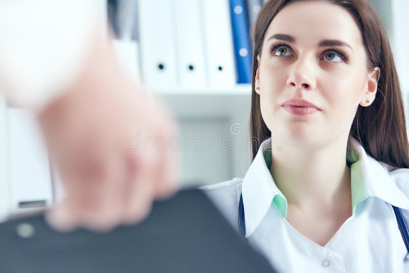 Frumoasă femeie doctoriță zâmbitoare ascultând cu atenție plângerile pacienților la biroul medical. asistență medicală sau royalty free stock photo