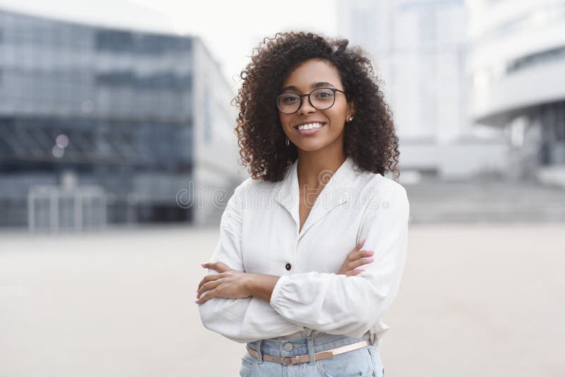 Frumoasă tânără portret într-un oraș. fată afro-americană zâmbitoare cu brațe încrucișate uitându-se la cameră. stock images