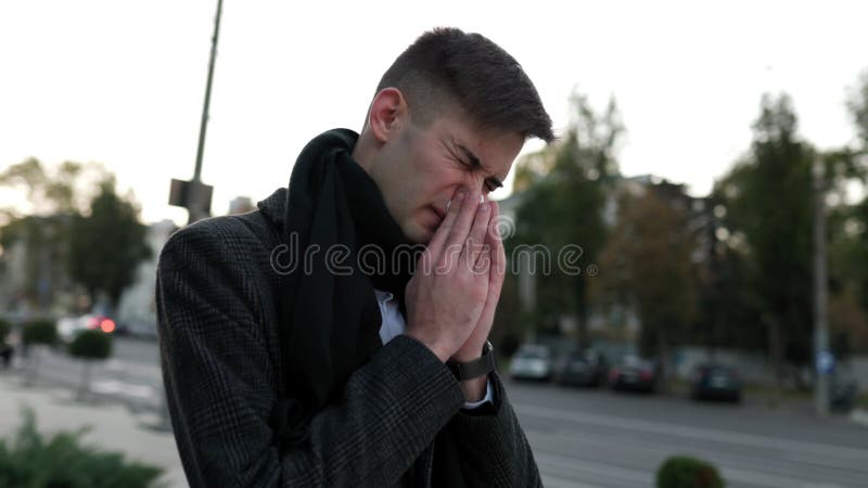 Frustración de la temporada de gripe joven estornuda y tos luchando contra el virus al aire libre metrajes