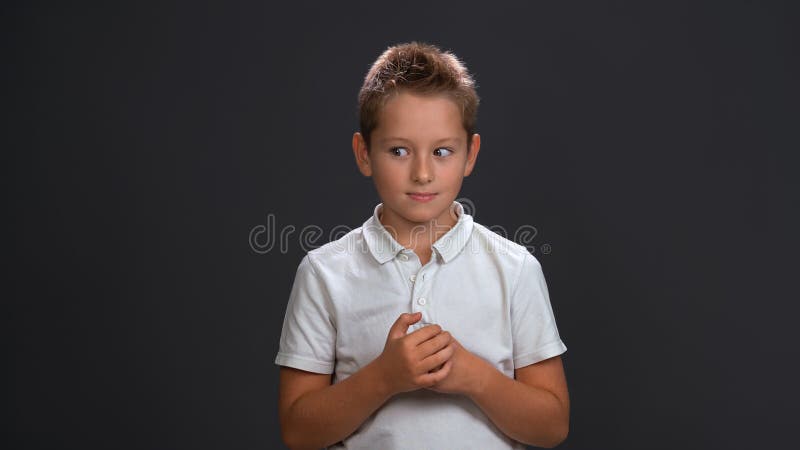 Frustrated boy in white shirt holding hands together in front of him while looking sideways at upper corner. Isolated on