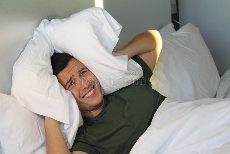 Frustrated man covering his ears with pillow royalty free stock photo Frustrated man covering his ears with pillow royalty free stock photo