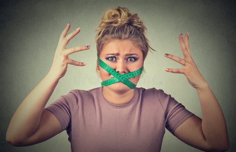 Frustrated woman with measuring tape around her mouth. Diet restriction and stress