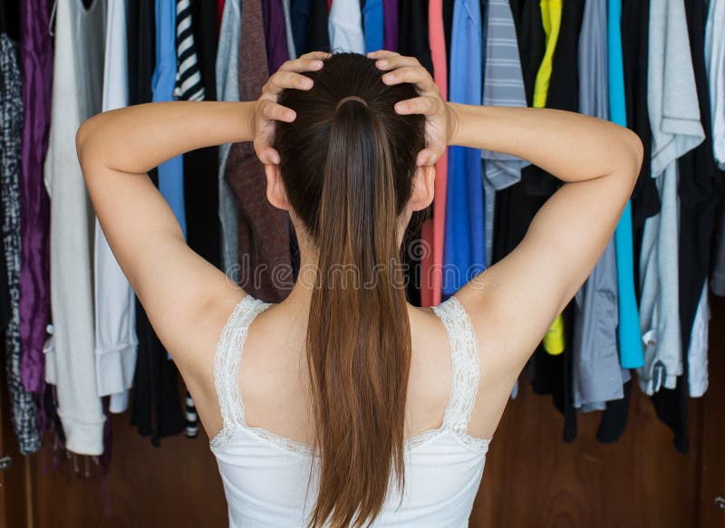 Frustrated young woman cannot decide what to wear from her close