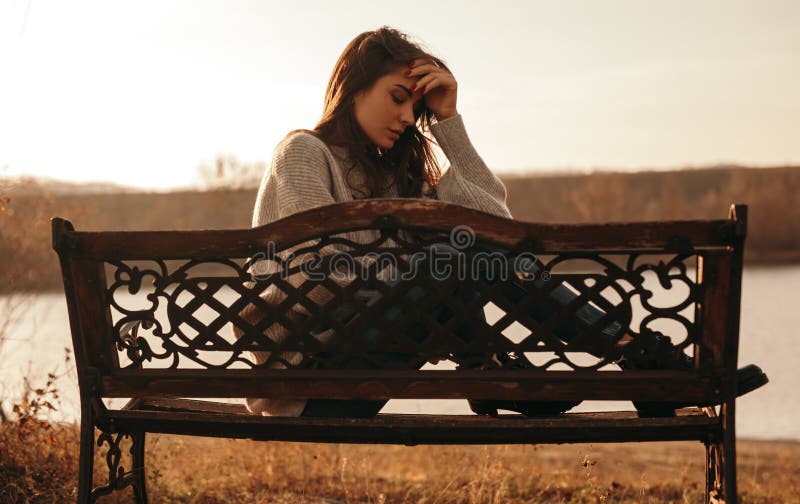 Frustrated young woman sitting on bench in park