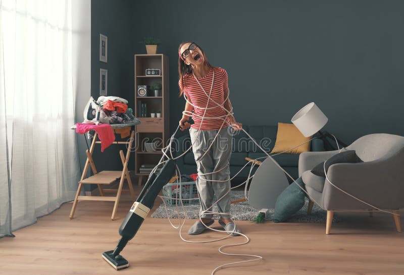 Frustrated housewife doing household chores at home: she is wrapped in cables, screaming and cleaning up a messy room. Frustrated housewife doing household chores at home: she is wrapped in cables, screaming and cleaning up a messy room