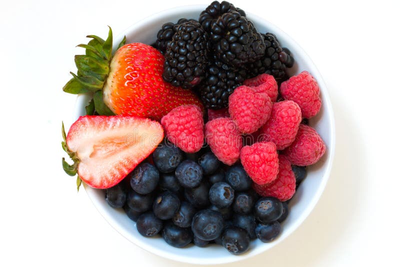 Frutta di bacche mista fresca organica in una ciotola sulla tavola immagini stock Frutta di bacche mista fresca organica in una ciotola sulla tavola immagini stock